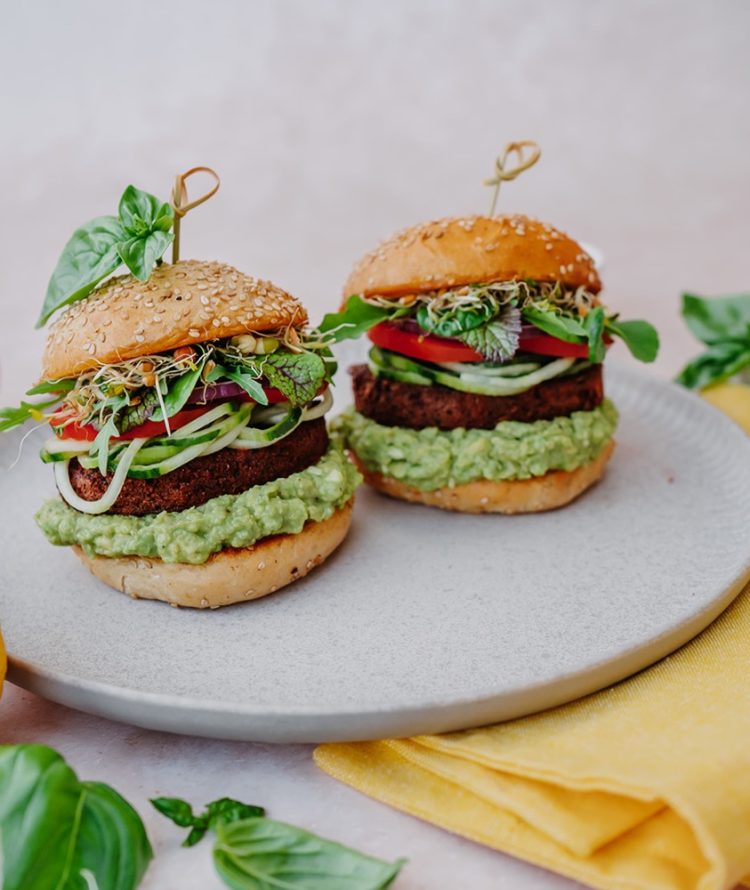 a plate of burgers with vegetables and herbs on it
